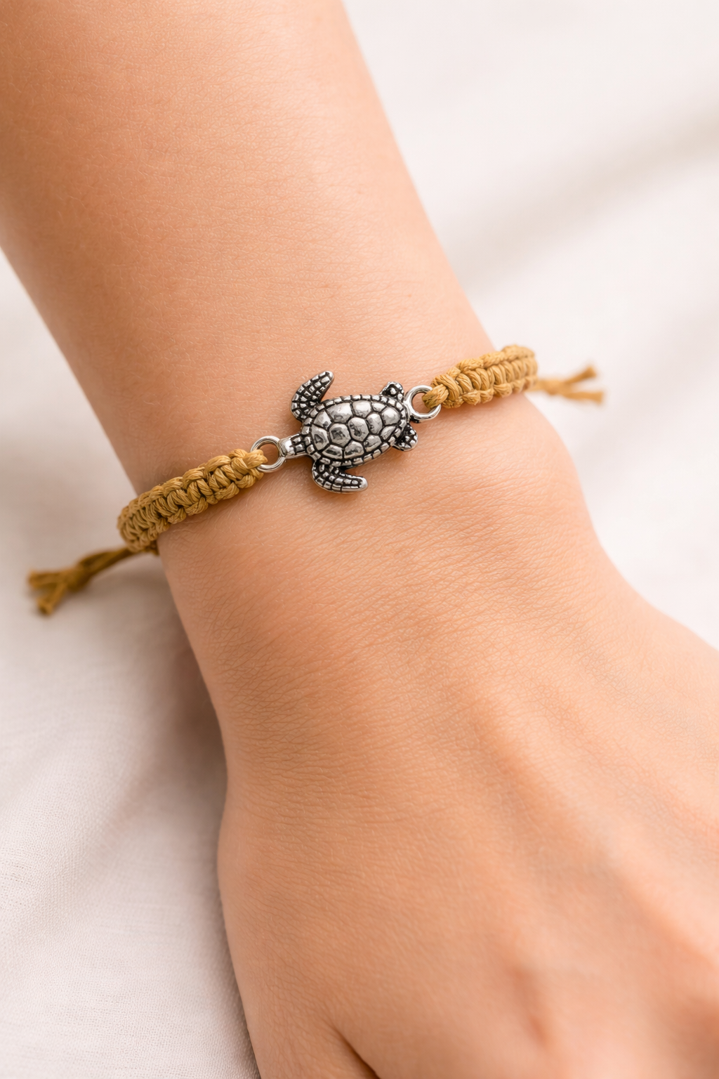 Adjustable macrame turtle bracelet with sea turtle charm on model wrist