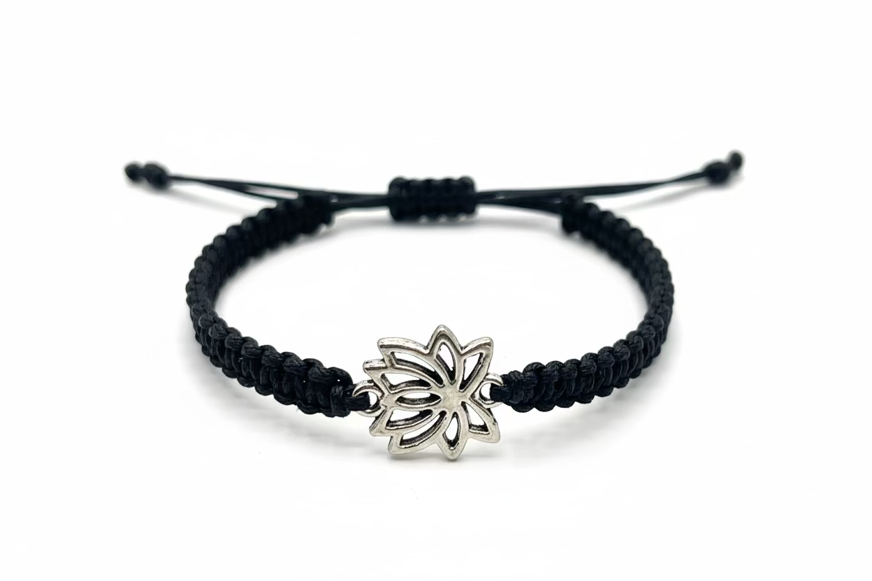 Black braided bracelet with a silver lotus flower charm on a white background