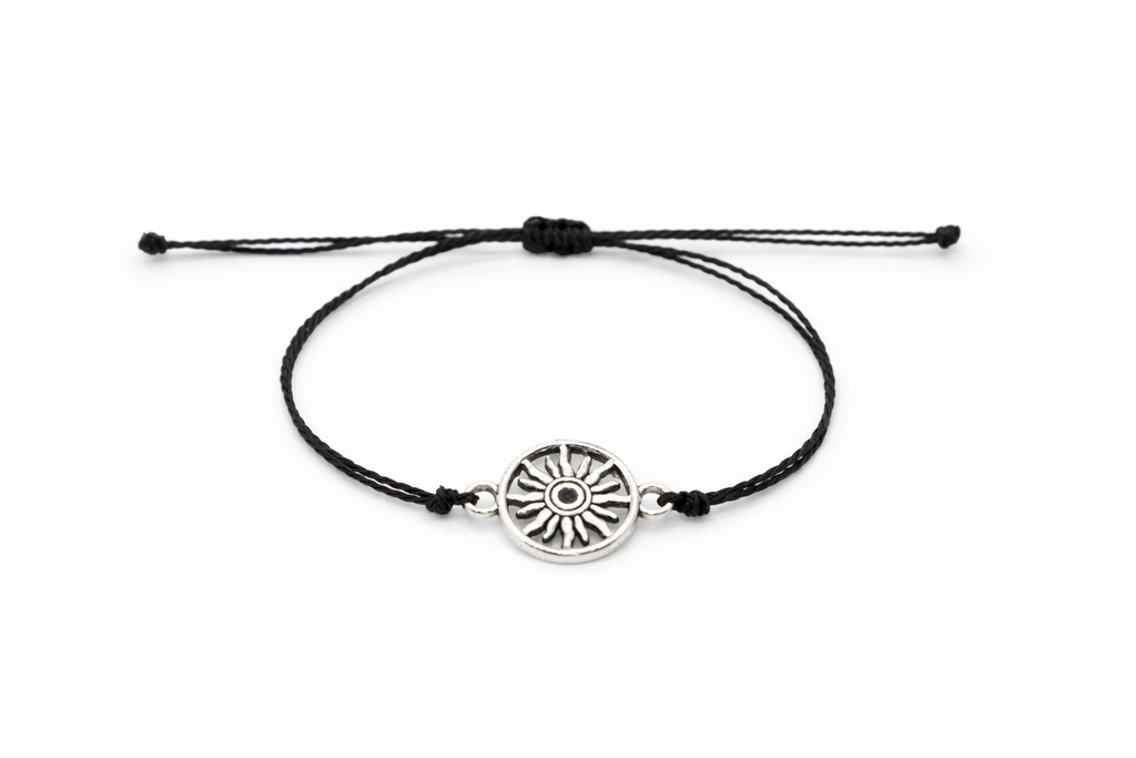 Black cord bracelet with a silver sun charm on a white background