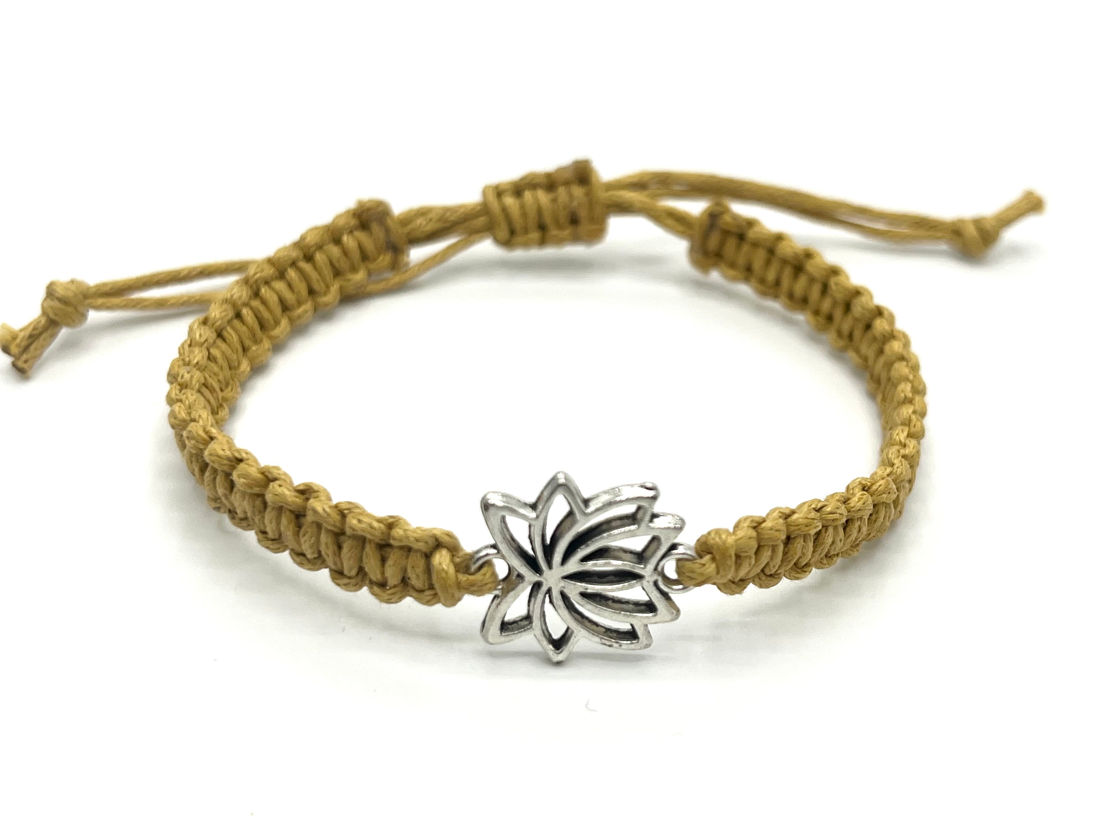 Bracelet with a star-shaped silver charm on a beige cord against a white background