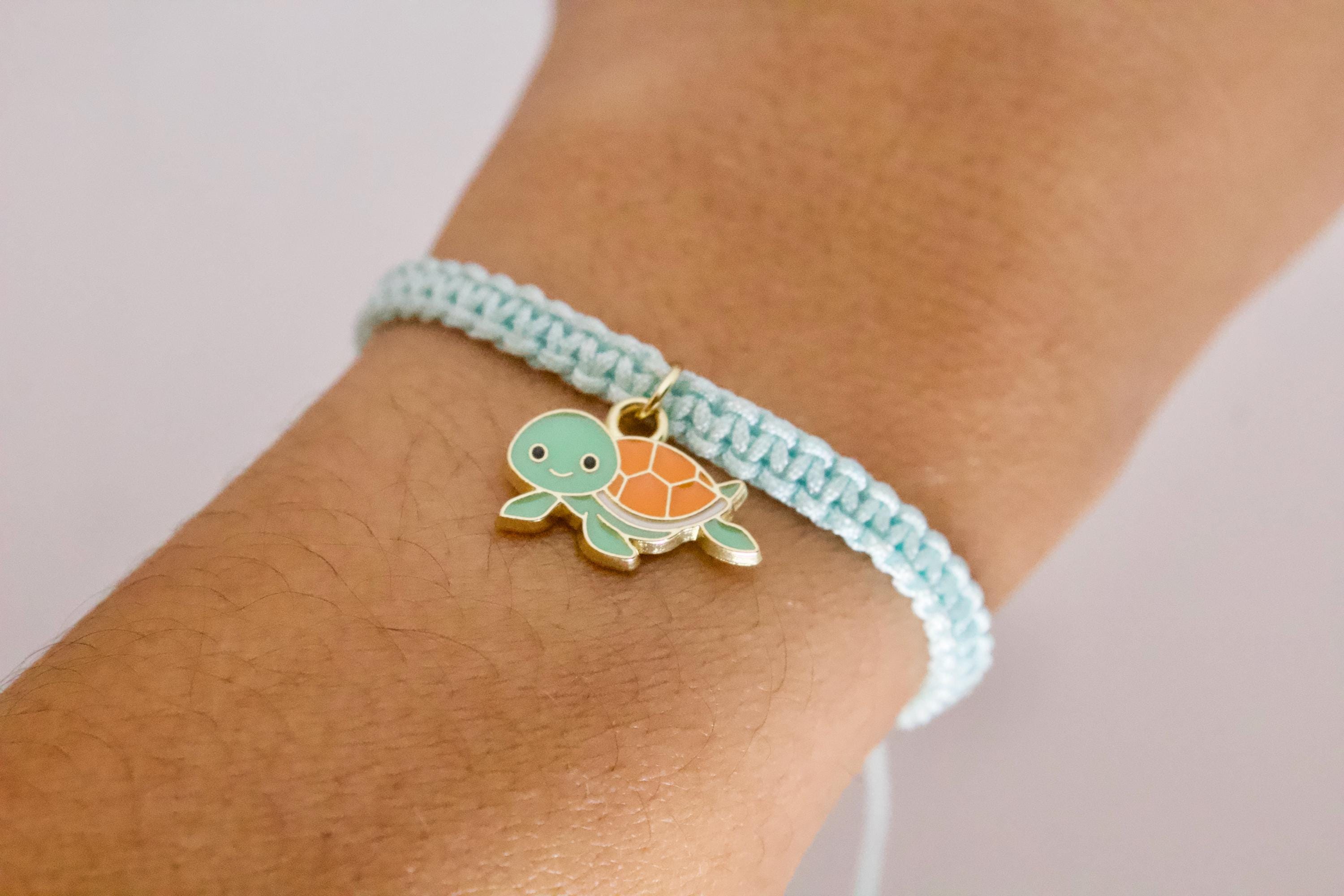 Turquoise bracelet with a turtle charm on a wrist against a light background