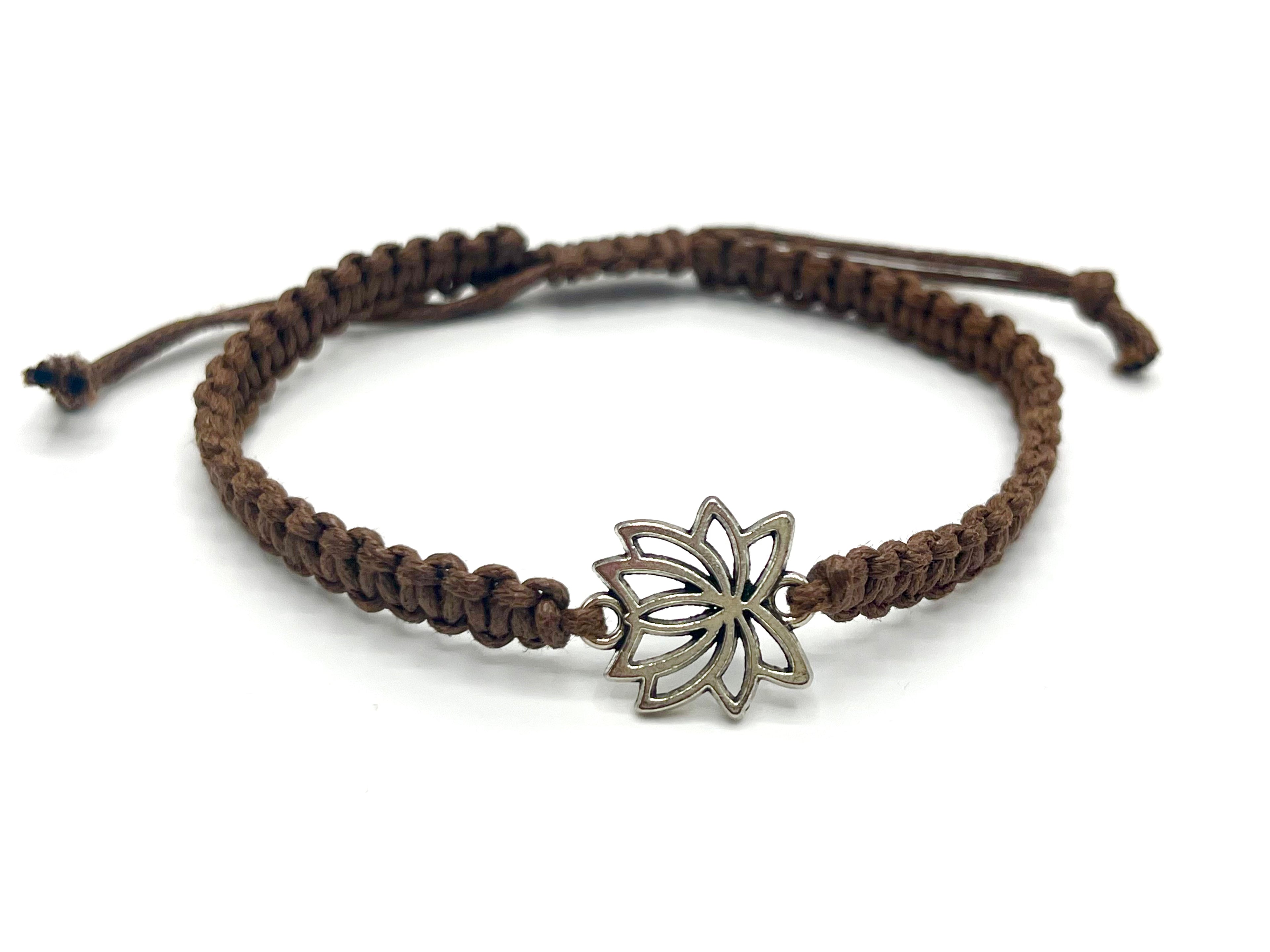Brown braided bracelet with a silver lotus flower charm on a white background