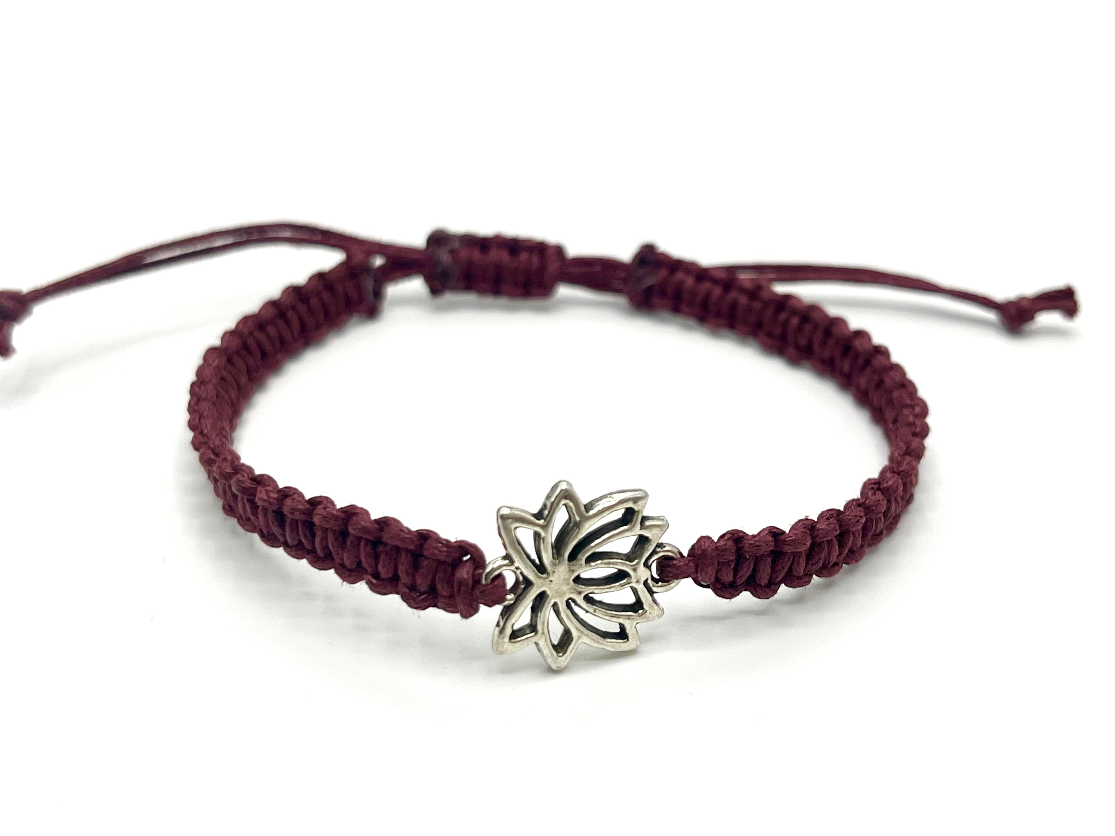 Burgundy braided bracelet with a silver lotus flower charm on a white background