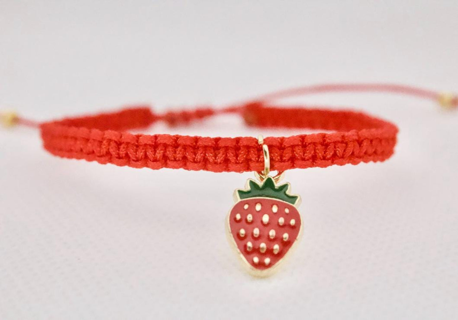 Close-up of strawberry charm on handmade macrame bracelet