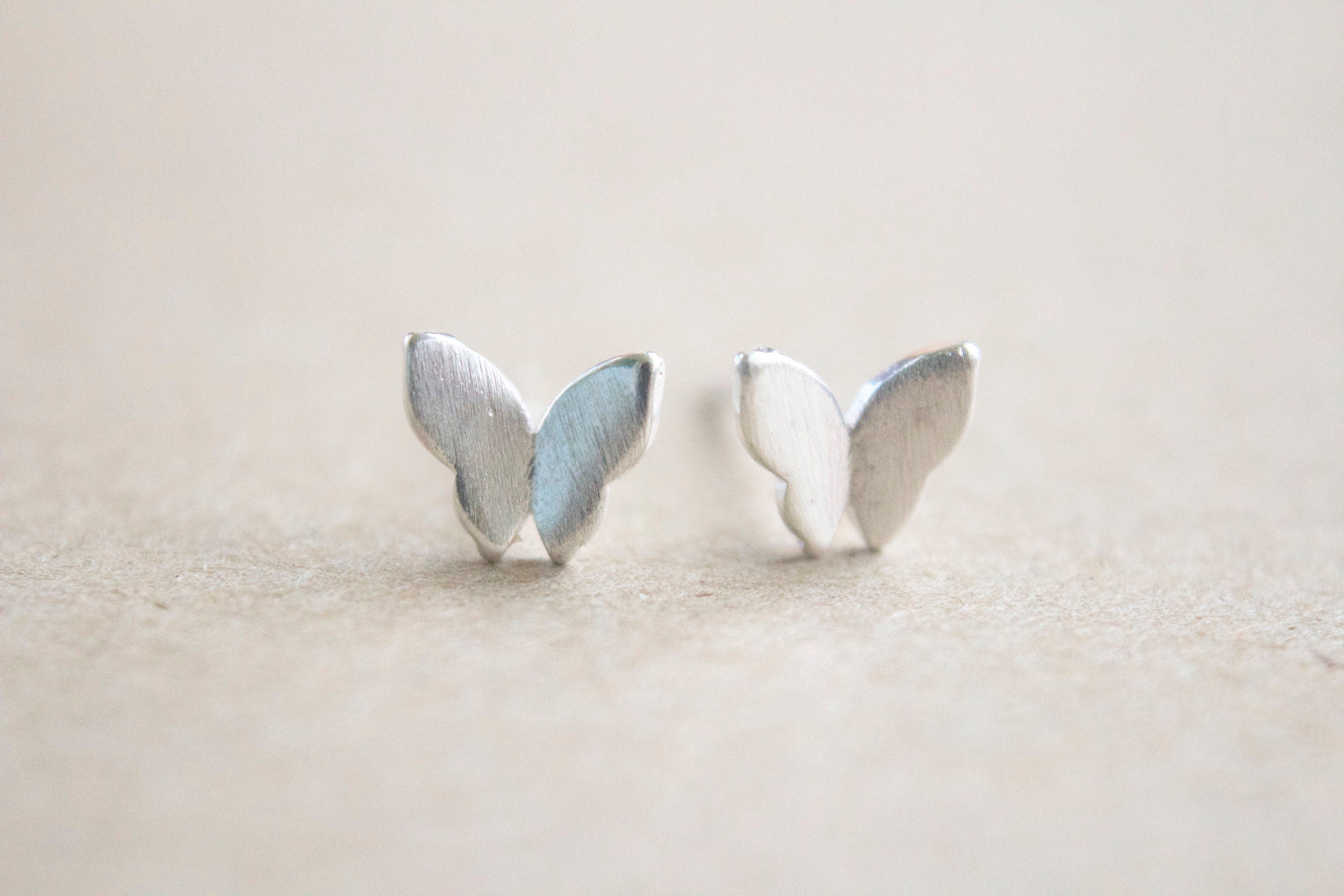 Close up of dainty sterling silver butterfly stud earrings
