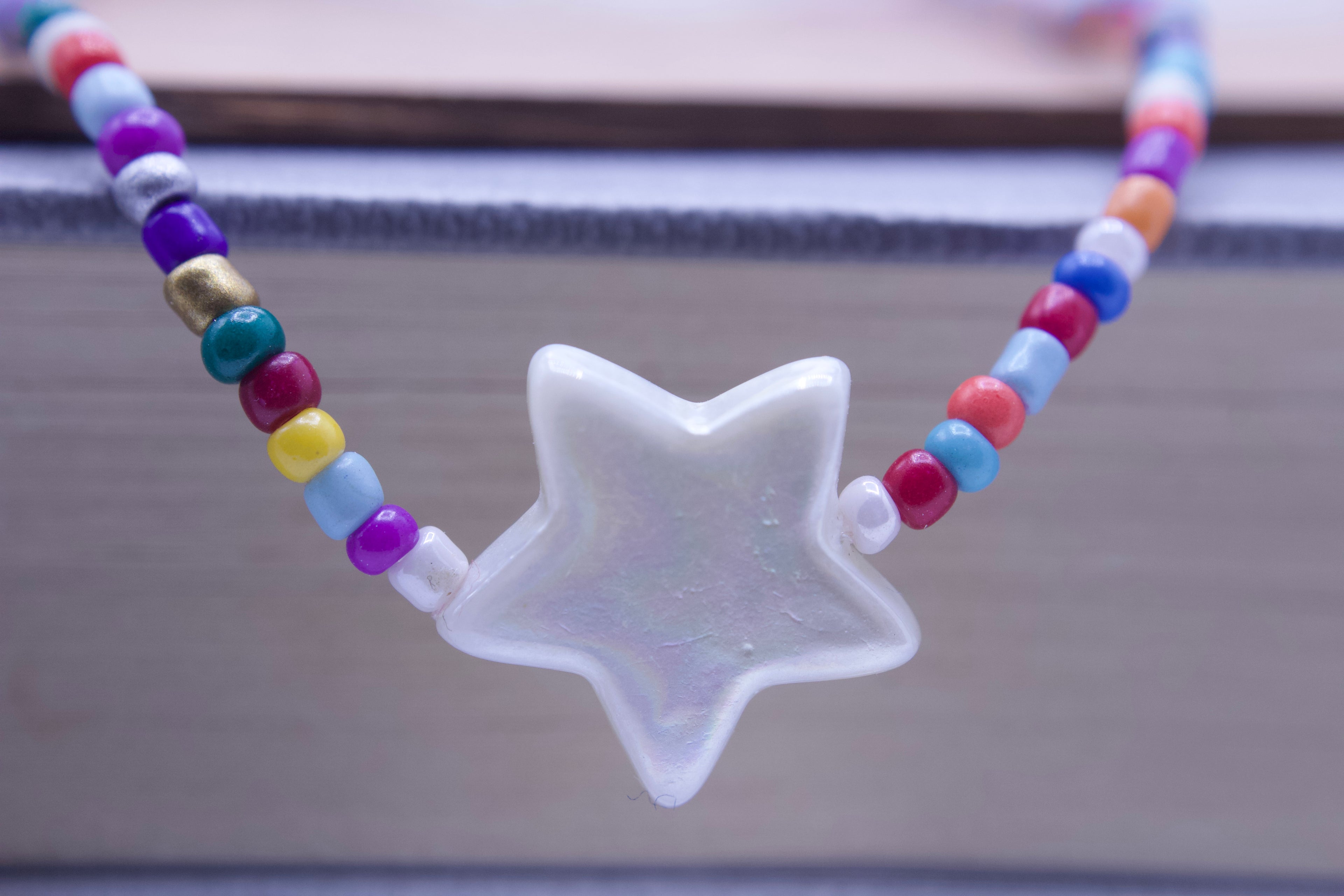Colorful beaded necklace with a star-shaped pendant on a blurred background