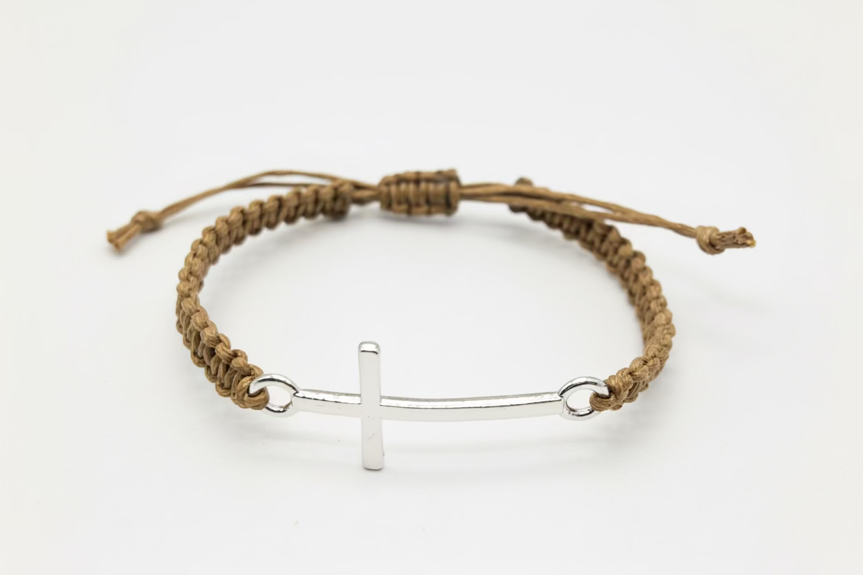Brown braided bracelet with a silver cross charm on a white background