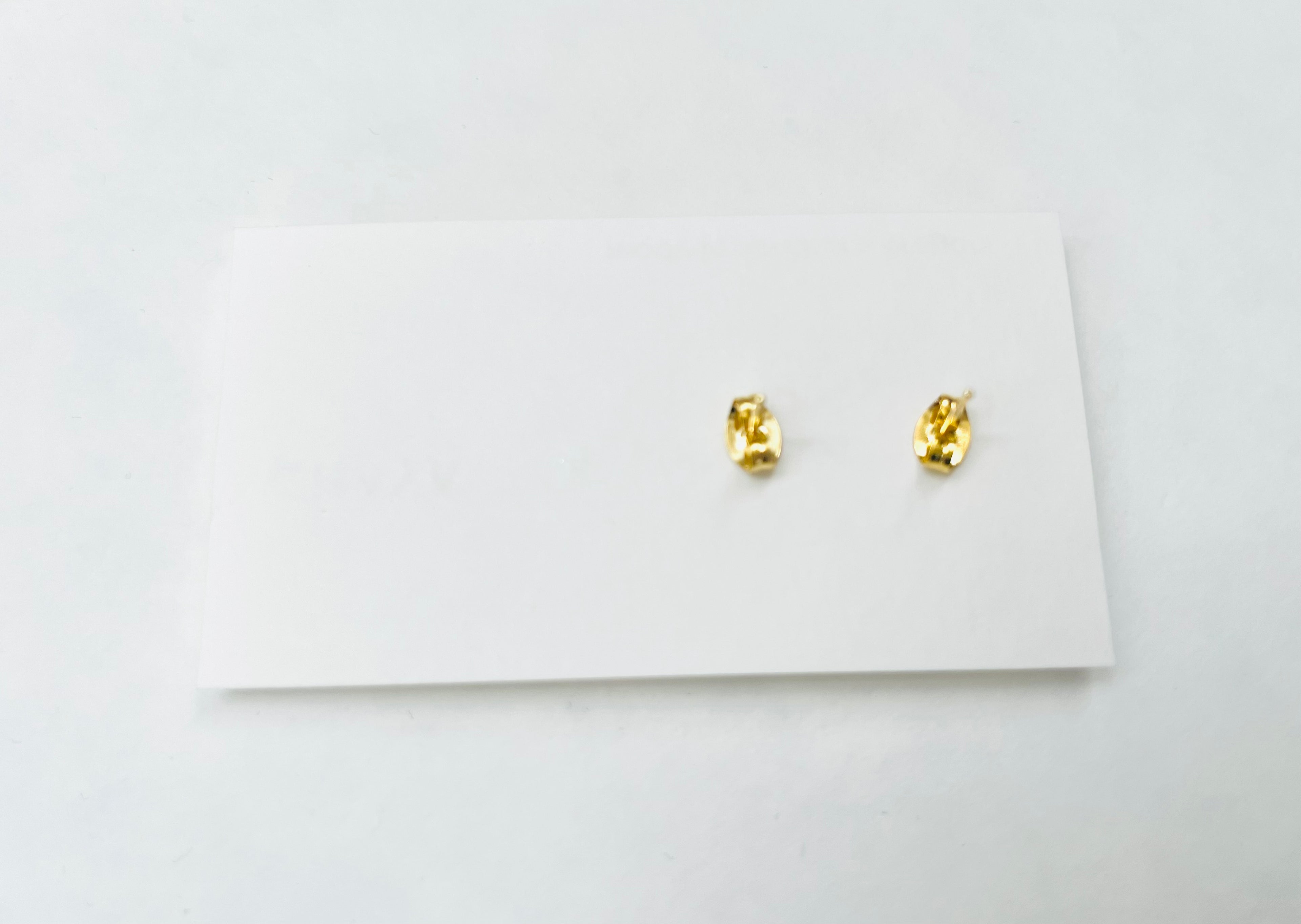Gold earrings on a white card with a white background