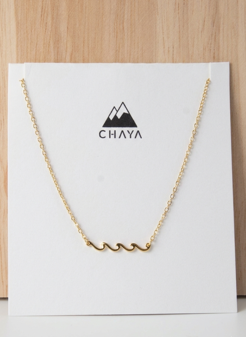 Gold necklace on a white card with 'Chaya' branding