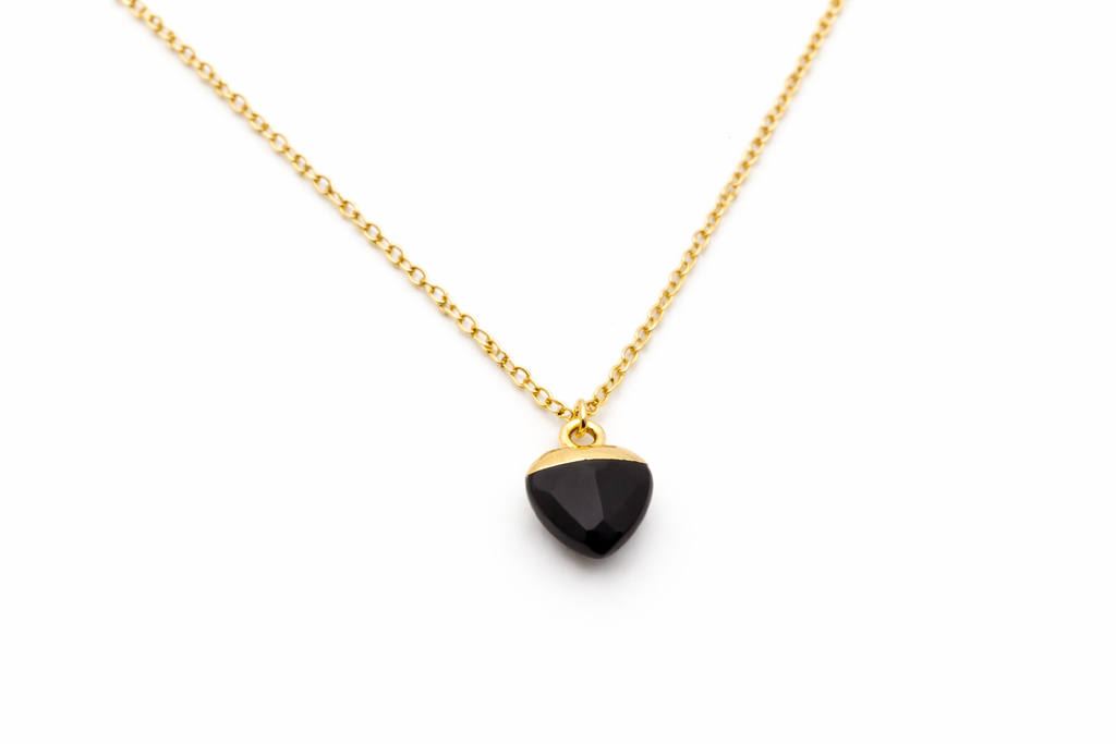 Gold necklace with a black pendant on a white background