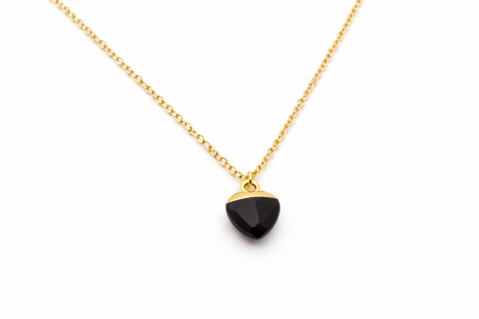 Gold necklace with a black pendant on a white background