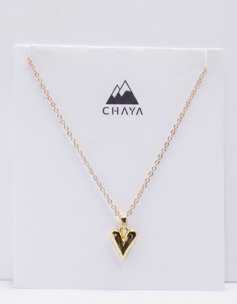 Gold necklace with a heart-shaped pendant on a Chaya branded card.