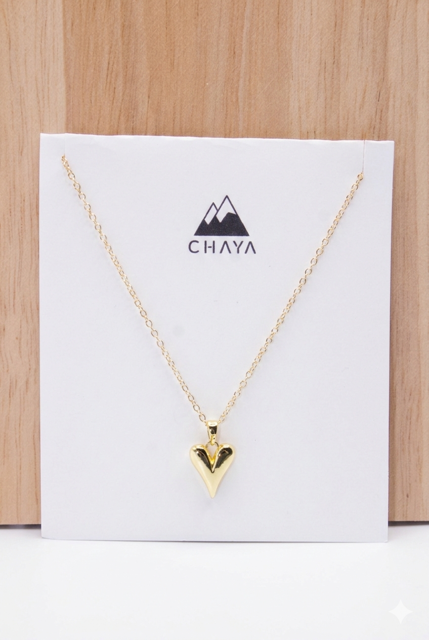 Gold necklace with a heart pendant on a Chaya branded card against a wooden background