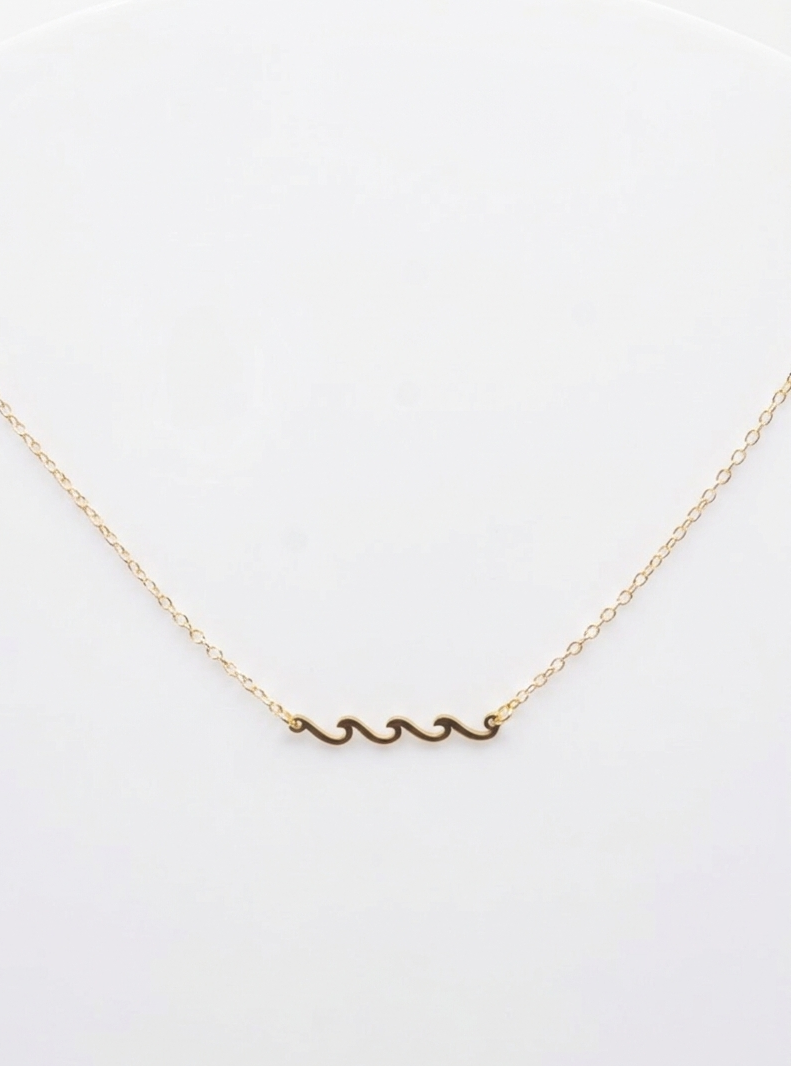 Gold necklace with a wave pendant on a white background