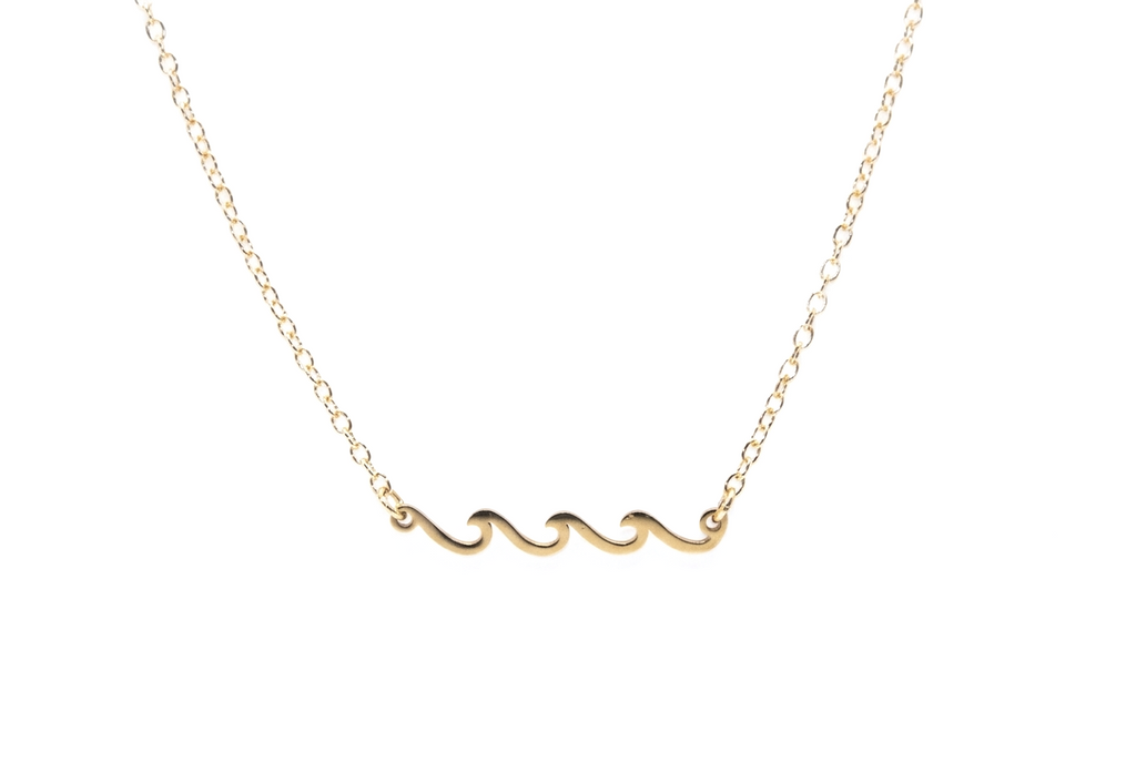 Gold wave necklace on a white background