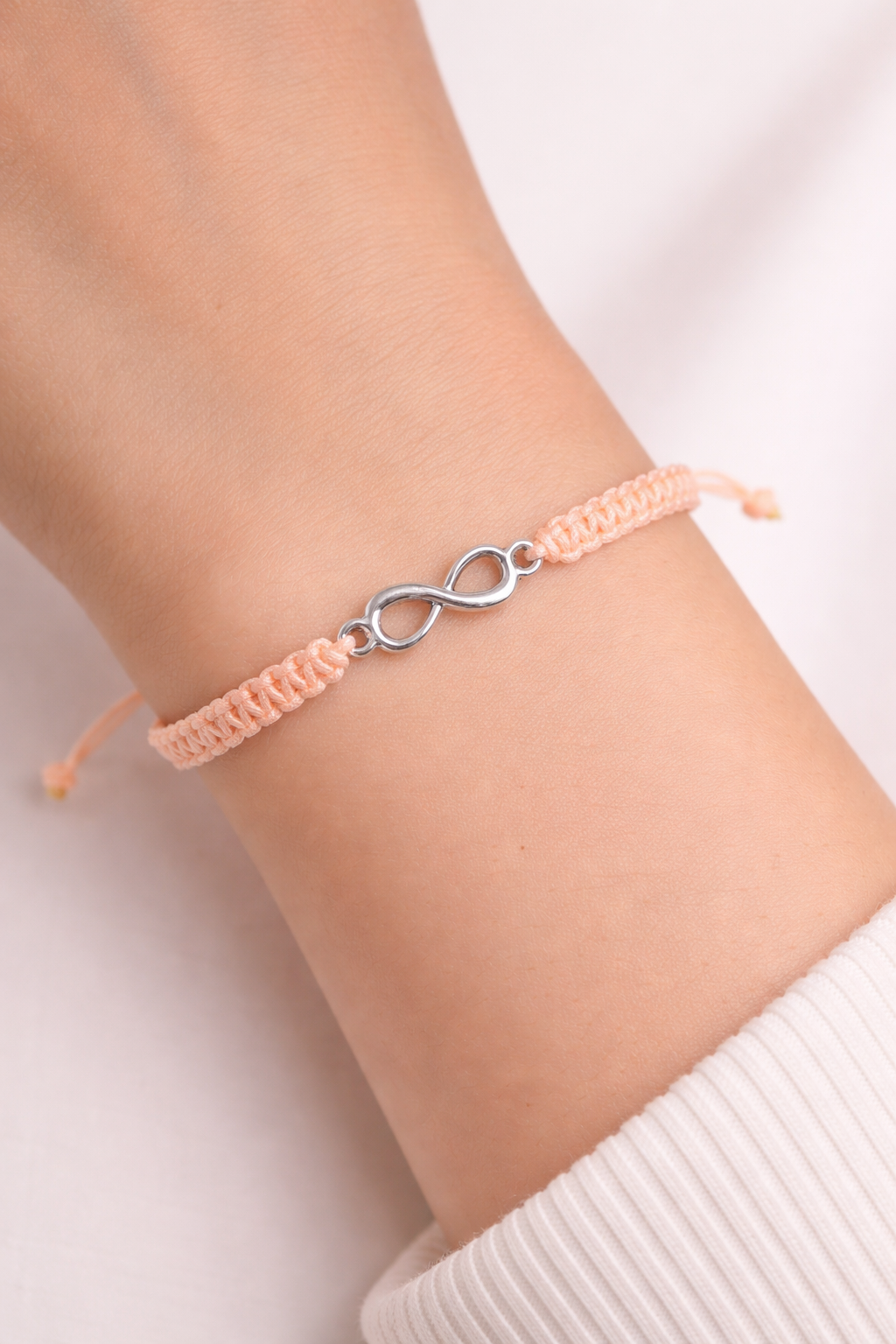 Infinity charm macrame bracelet on wrist, handmade adjustable bracelet by Chaya Jewelry