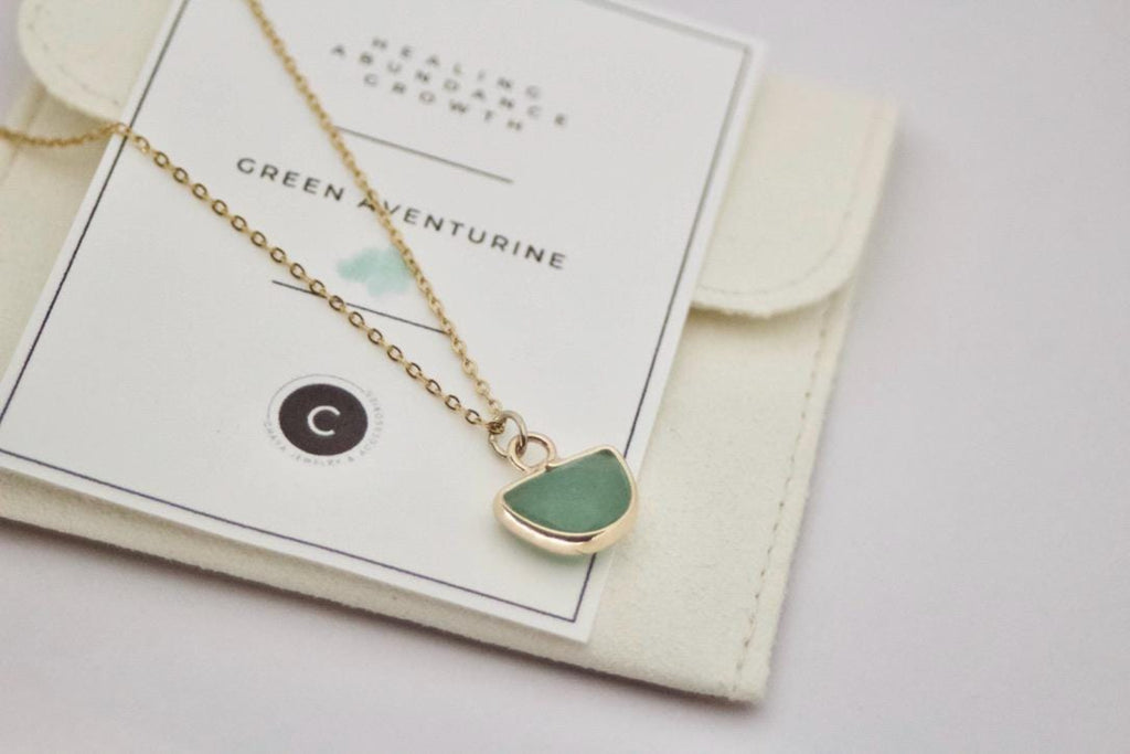 Necklace with a green pendant on a card with product details