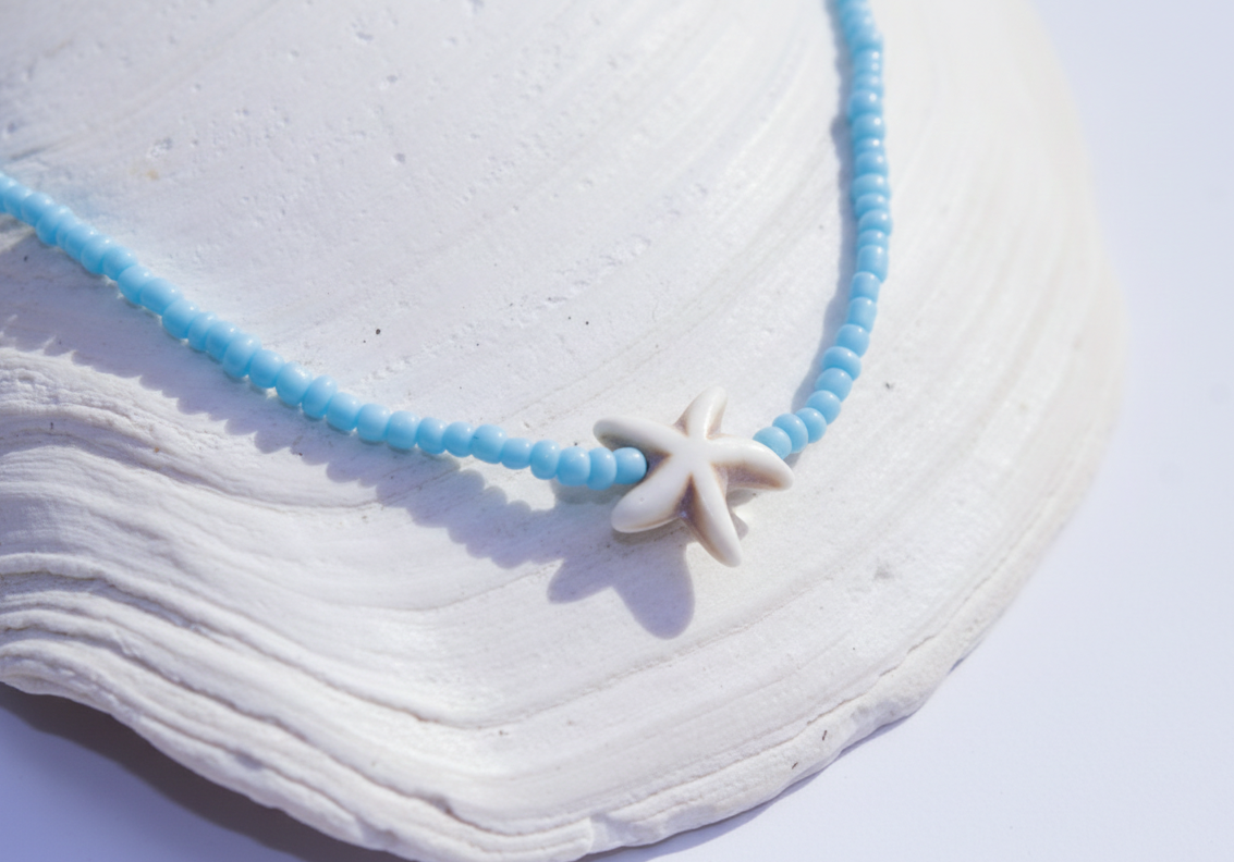 Necklace with a starfish charm on a white shell background