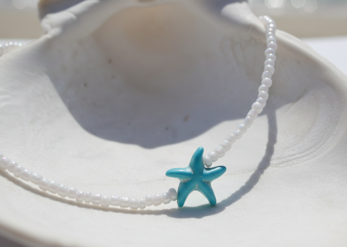 Necklace with a turquoise starfish pendant on a white shell background