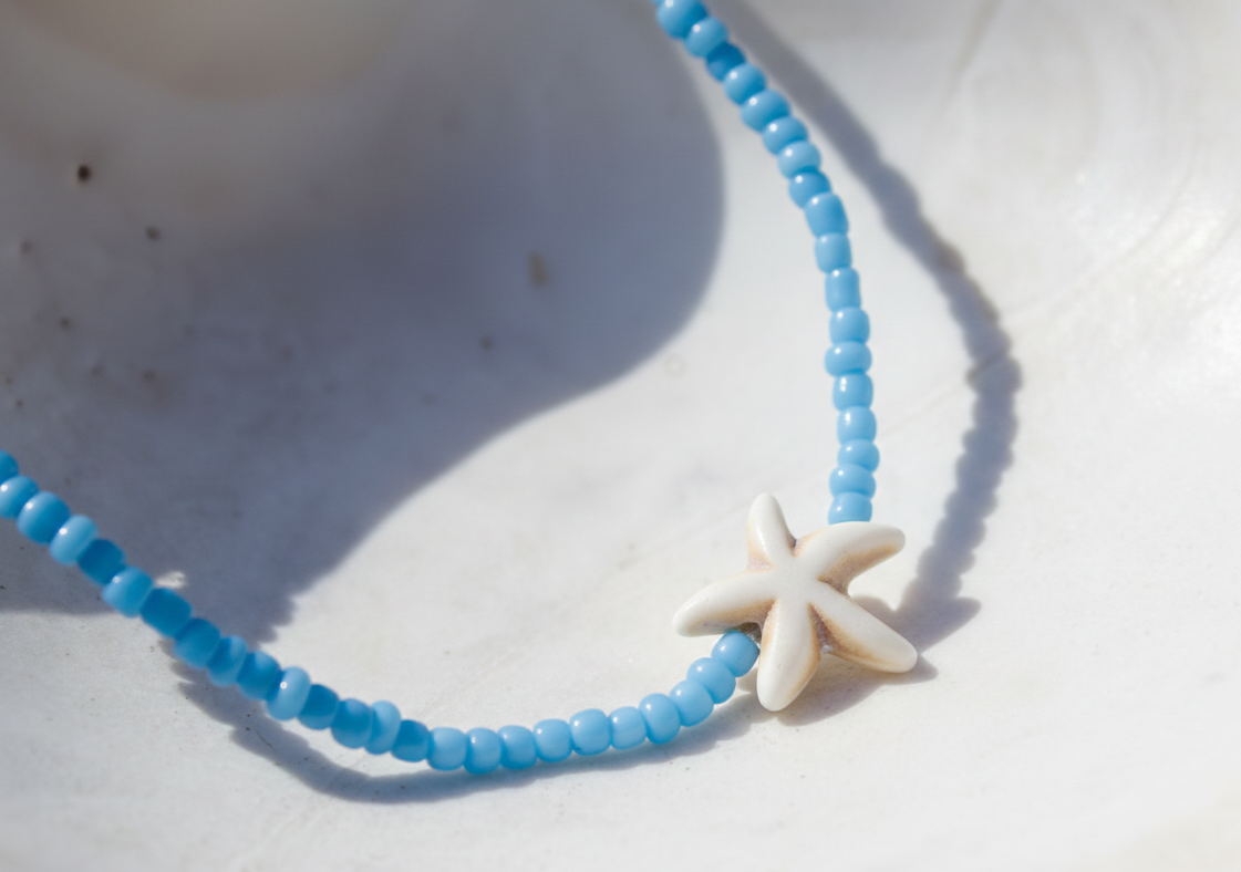 Blue beaded necklace with a starfish charm on a white surface