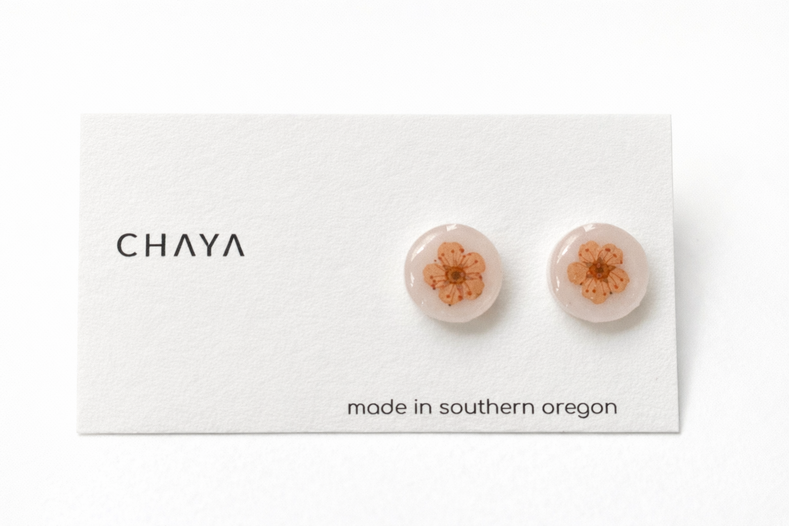 Pair of earrings with floral design on a Chaya branded card.