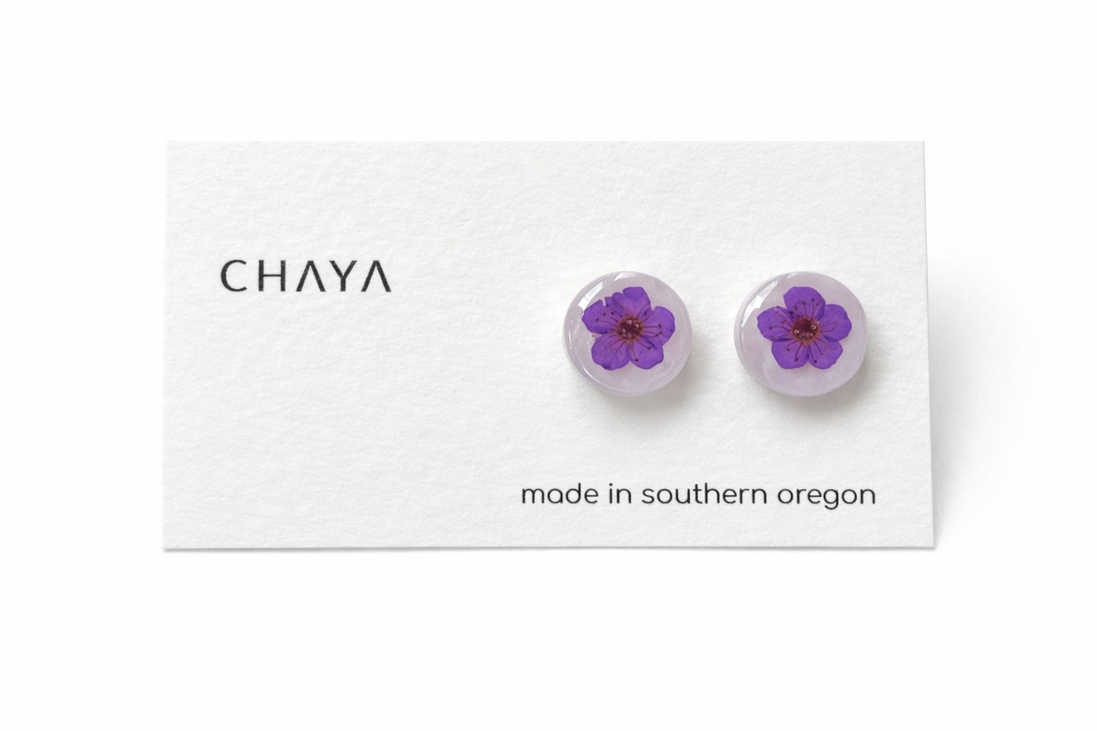 Pair of earrings with purple flowers on a Chaya branded card.
