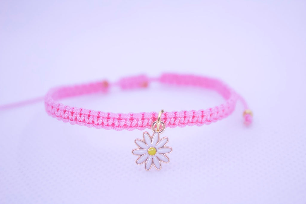 Pink bracelet with a daisy charm on a light purple background