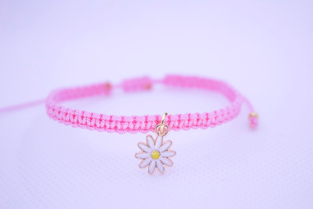 Pink bracelet with a daisy charm on a light purple background