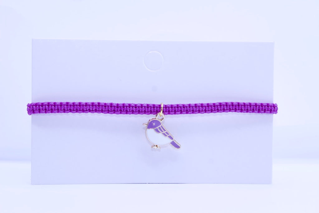 Purple bracelet with a bird charm on a light purple background