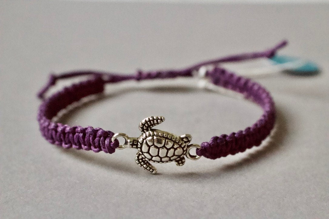 Purple bracelet with a turtle charm on a light gray background