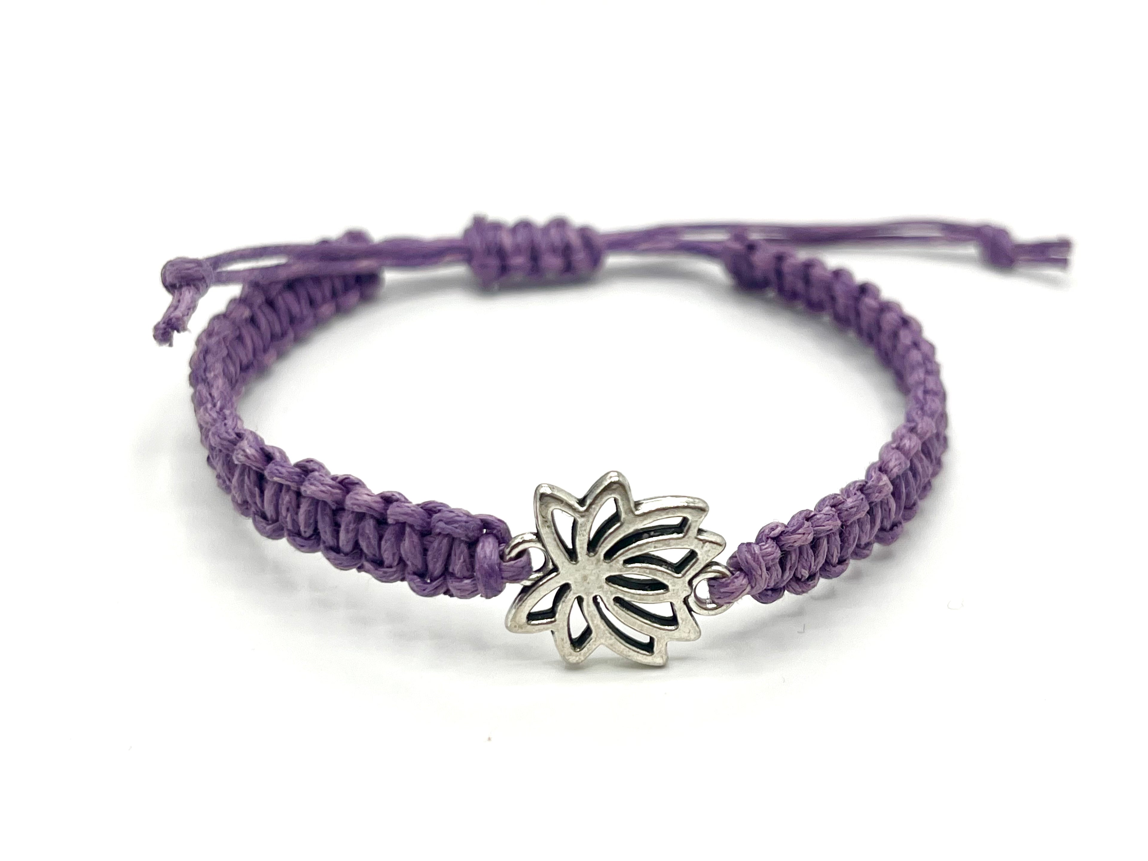 Purple braided bracelet with a silver lotus flower charm on a white background