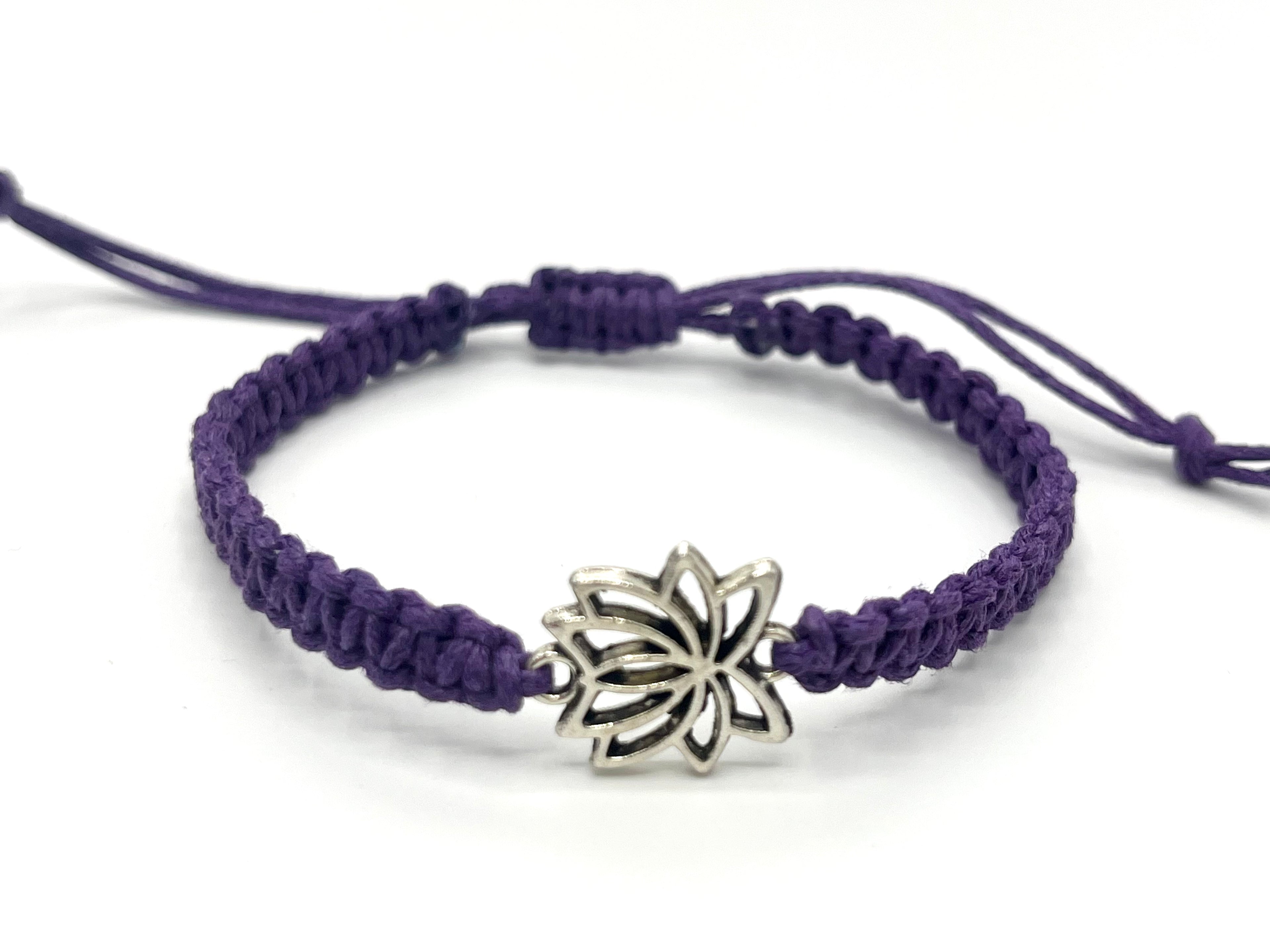 Purple macrame bracelet with a silver lotus flower charm on a white background