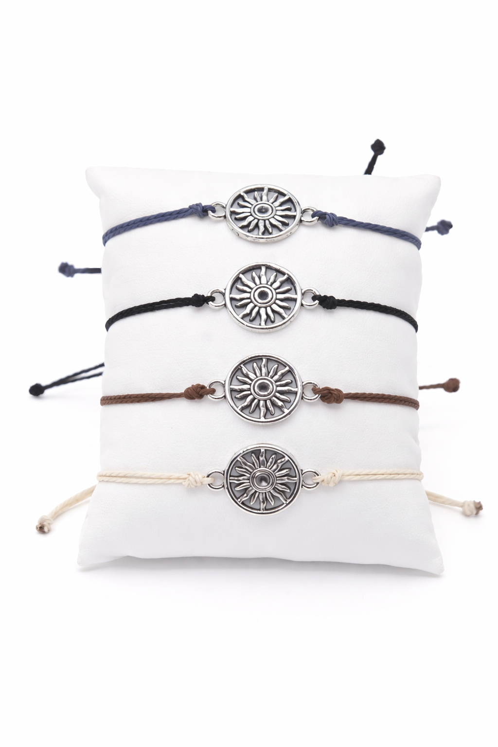 Set of four bracelets with sun-shaped silver charms on a white pillow