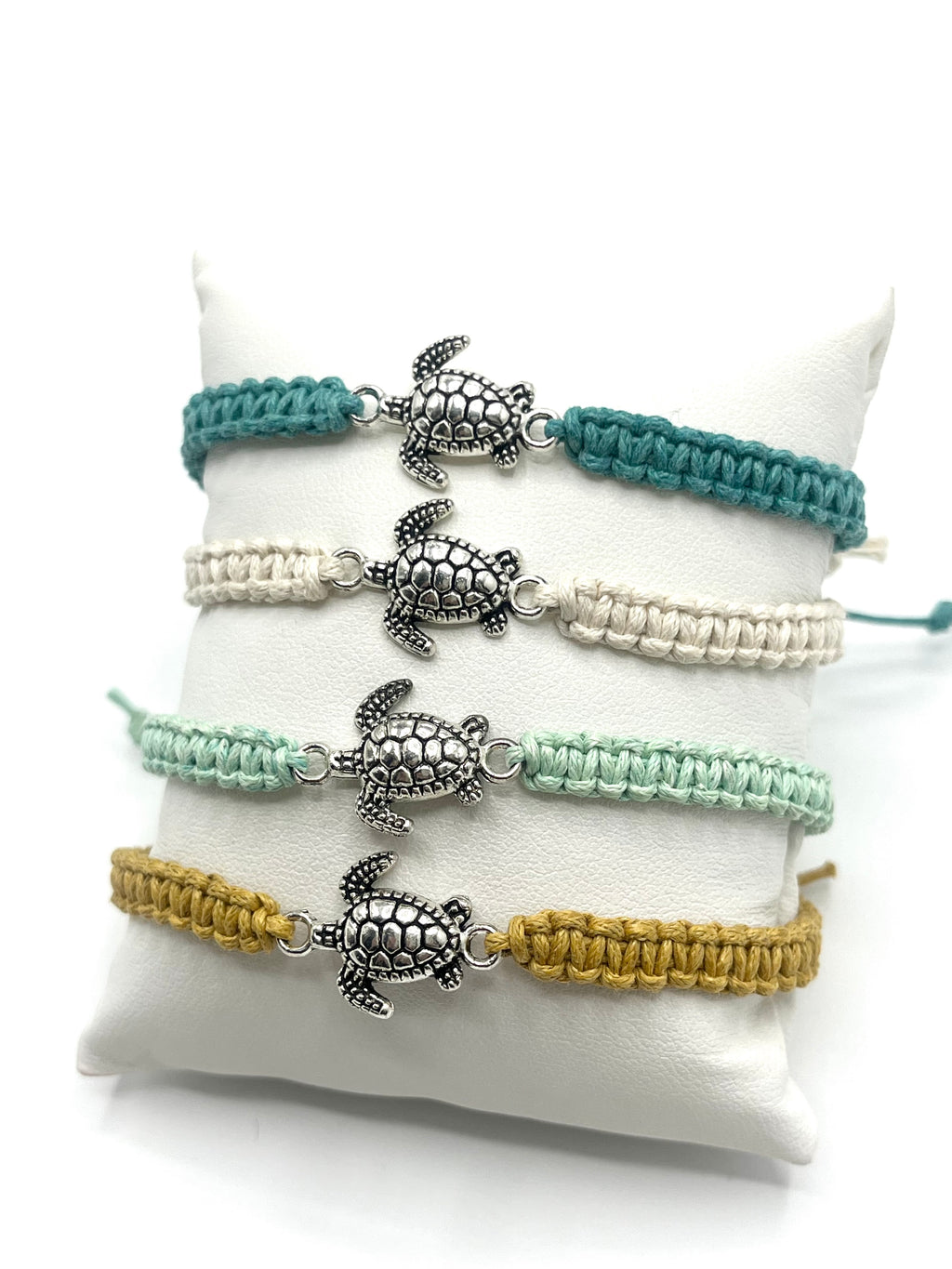 Set of four turtle-themed bracelets in different colors on a white cushion