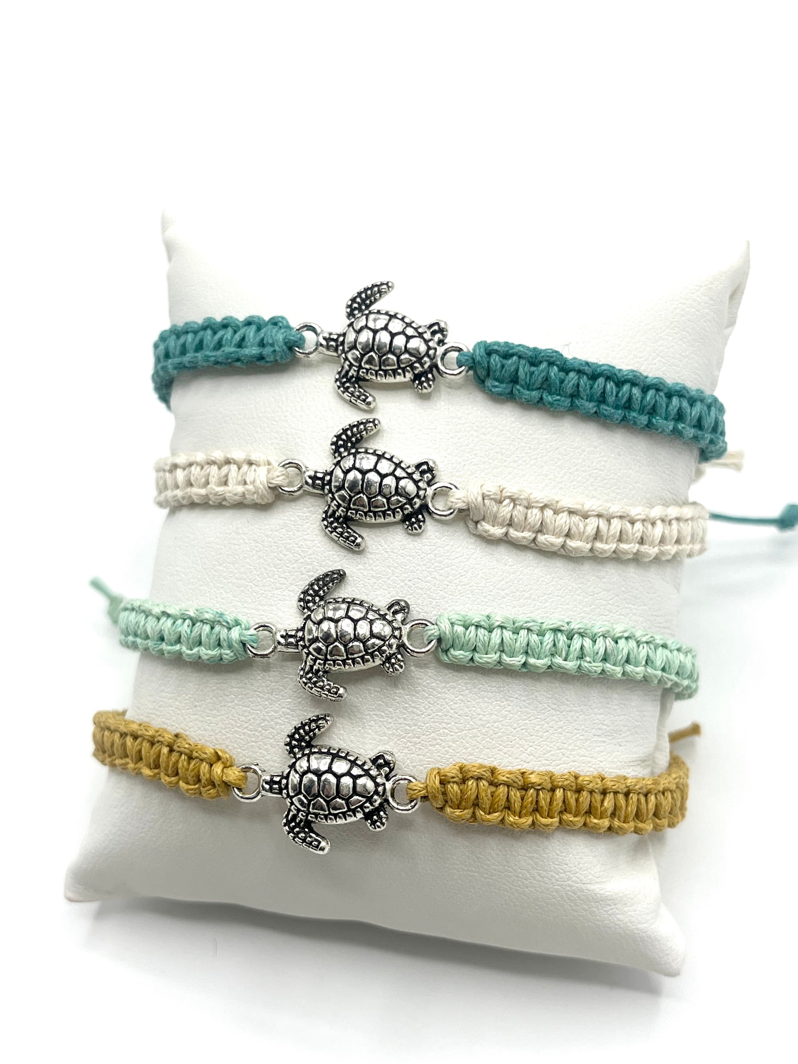 Set of four turtle-themed bracelets in different colors on a white cushion