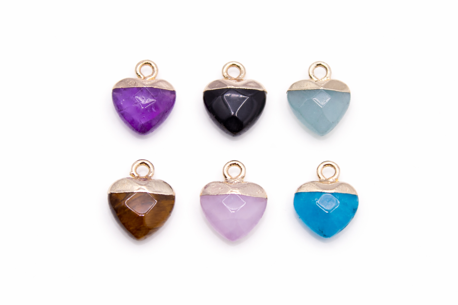 Set of heart-shaped gemstone pendants in various colors on a white background