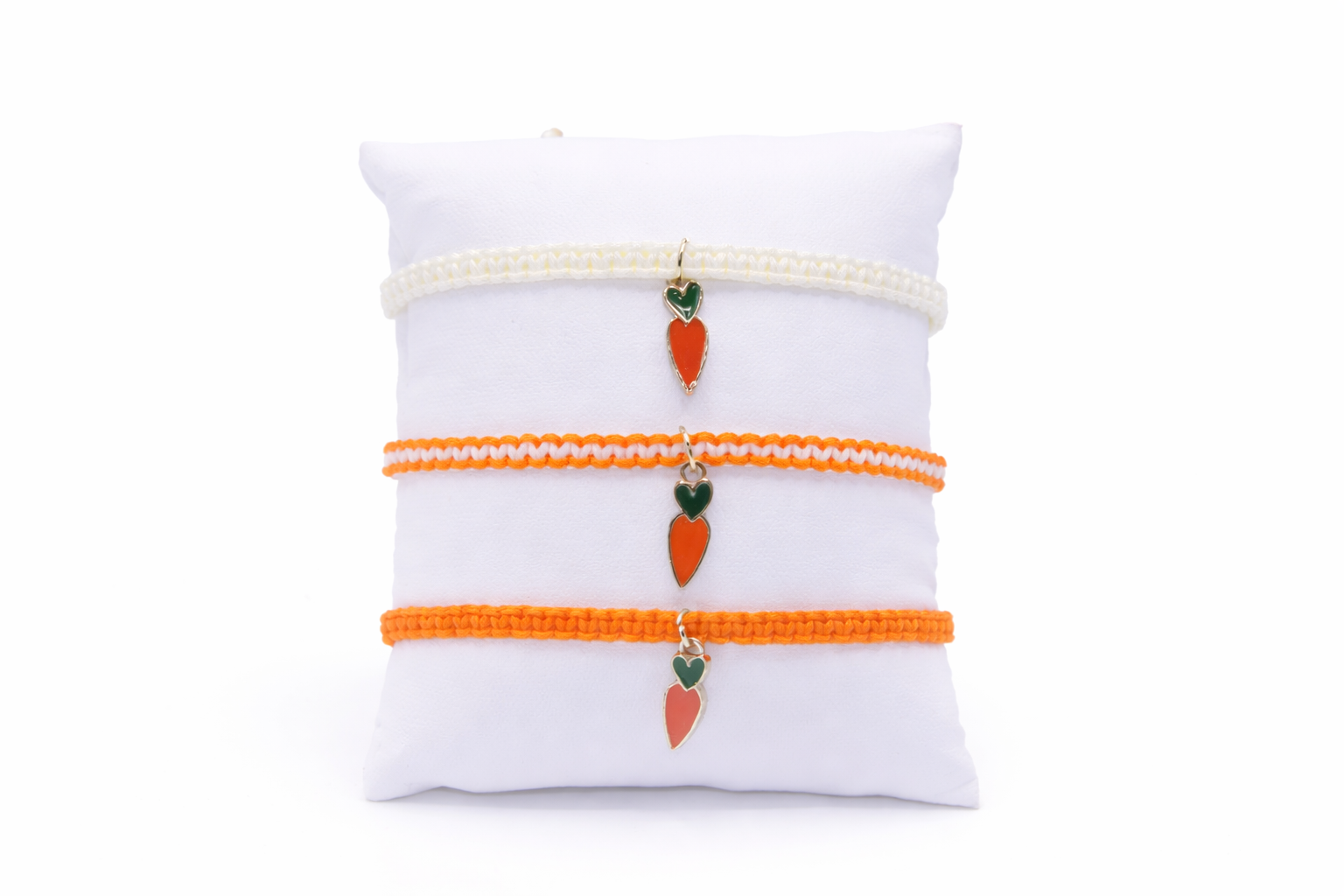 Set of three bracelets with carrot charms on a white pillow