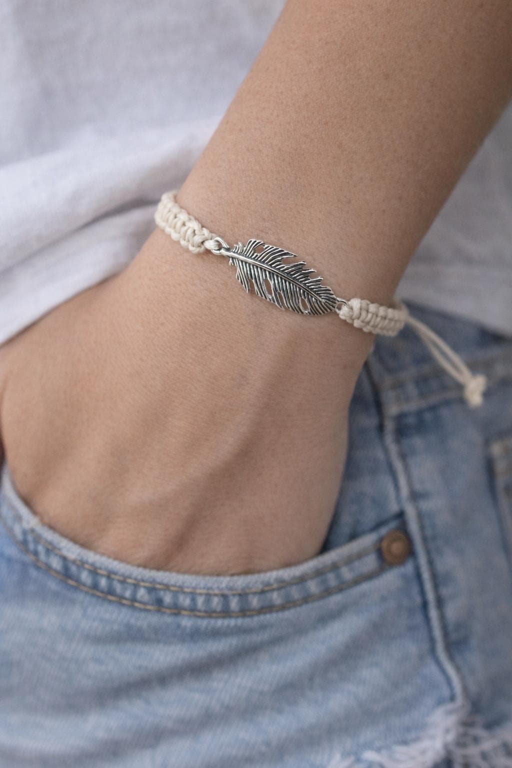 Silver feather bracelet on a wrist with a blurred background