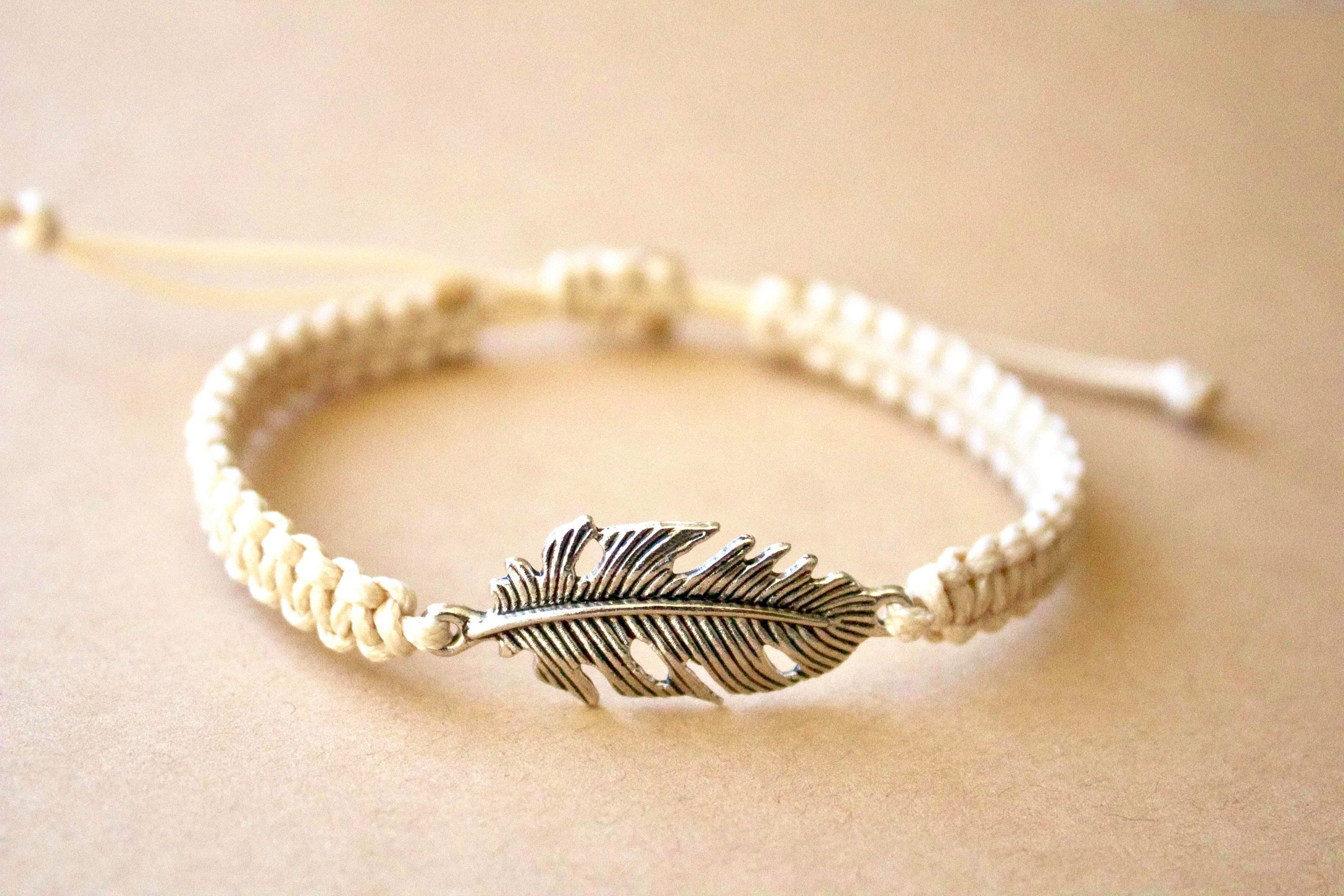 Bracelet with feather charm on a beige background
