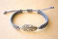 Bracelet with feather charm on a beige background