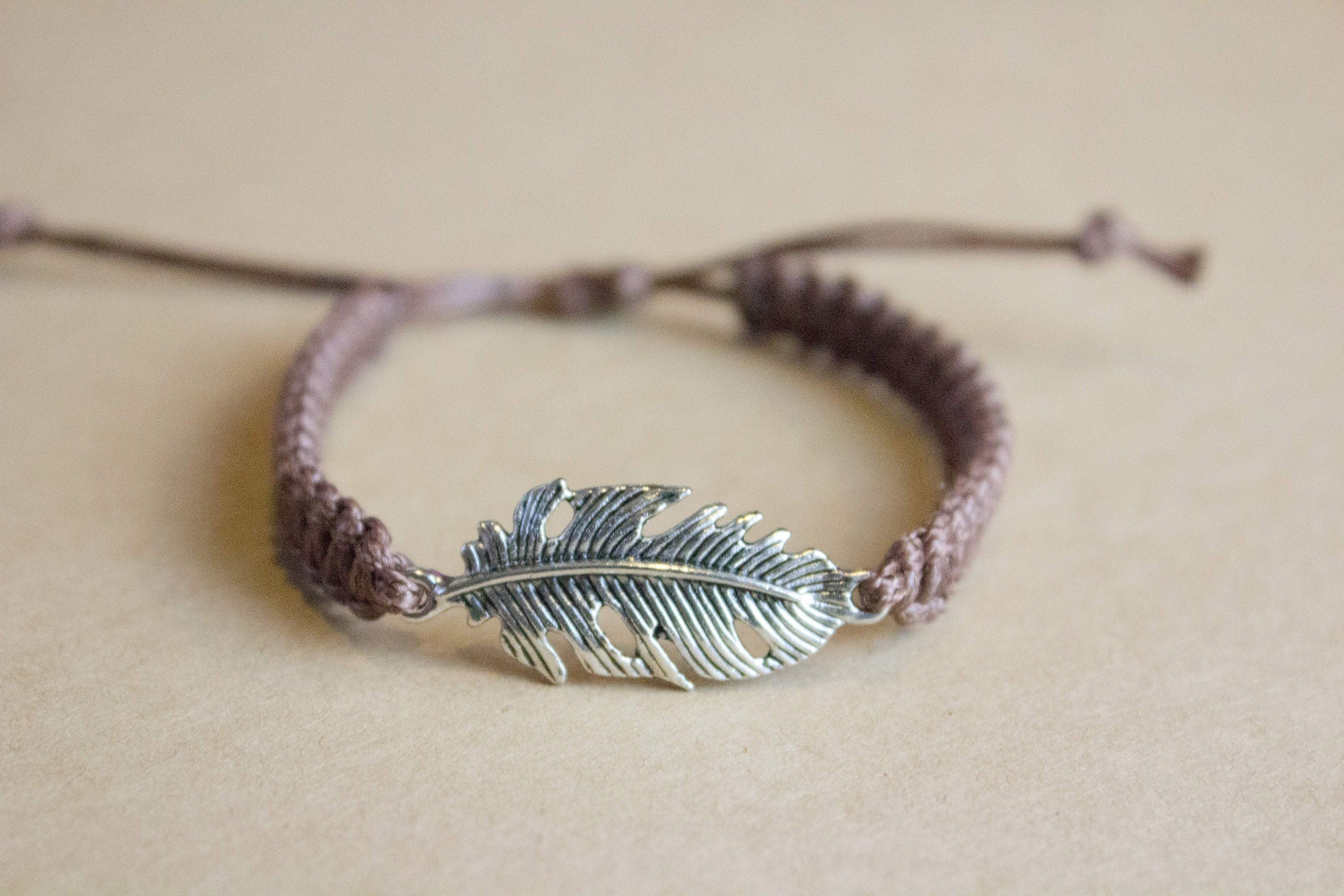 Bracelet with feather charm on a beige background