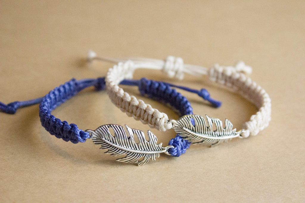 Two bracelets with feather designs on a beige background