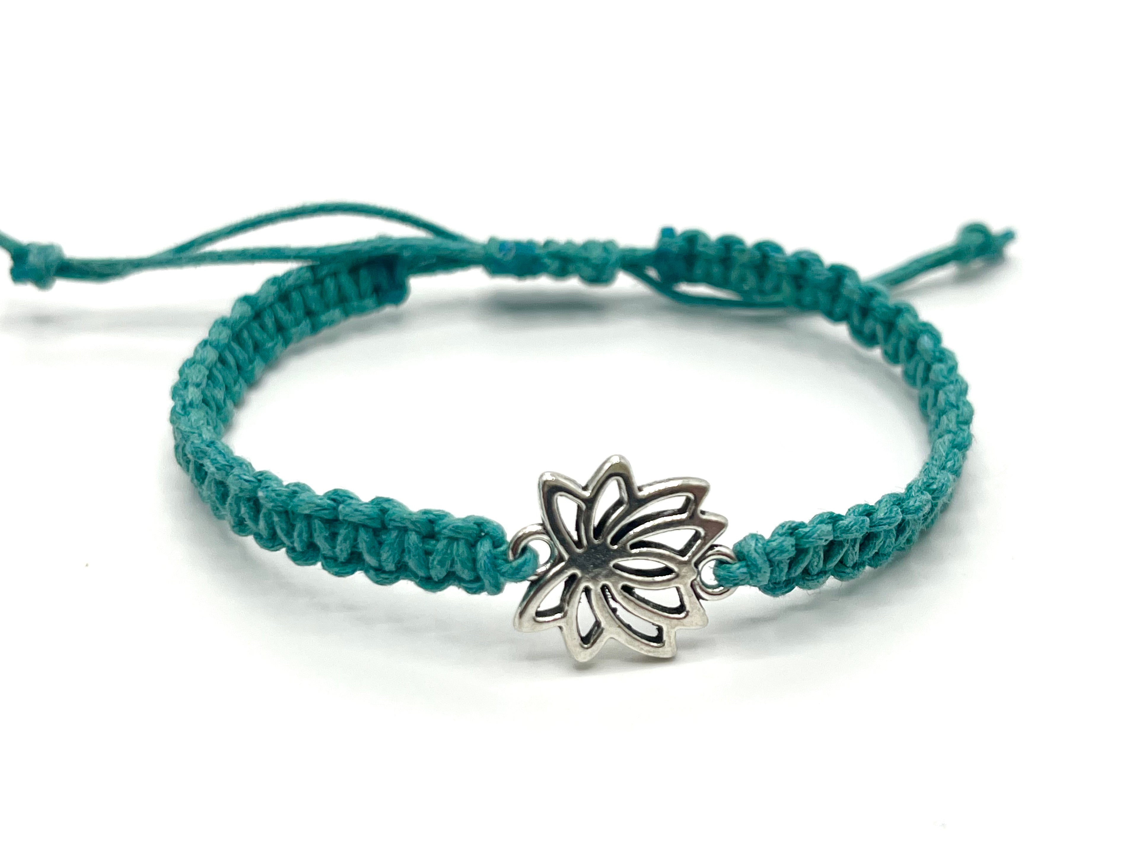 Teal braided bracelet with a silver butterfly charm on a white background