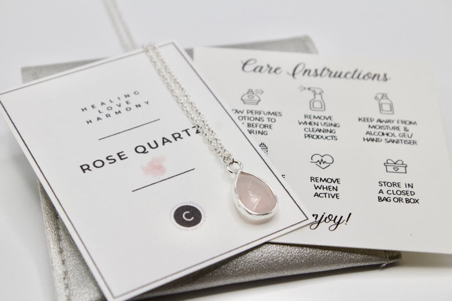 Necklace with rose quartz pendant on a branded card with care instructions.