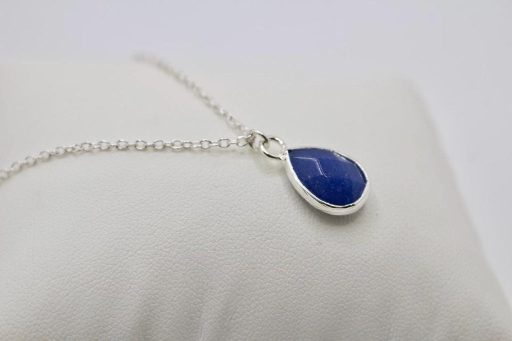 Necklace with a blue teardrop pendant on a light gray background