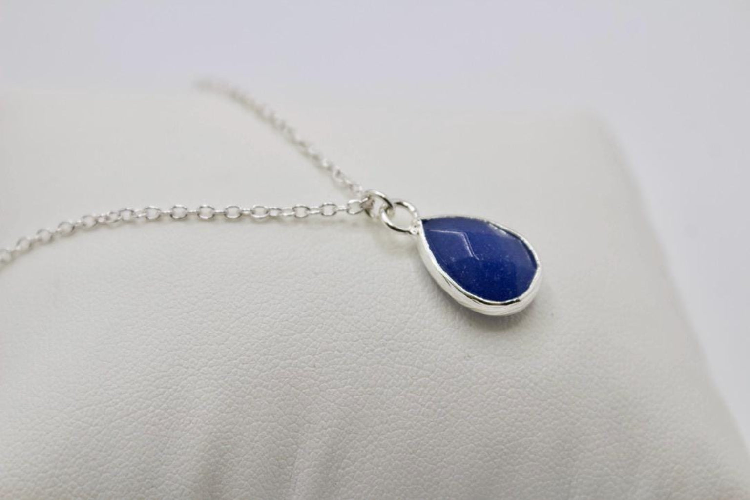 Necklace with a blue teardrop pendant on a light gray background