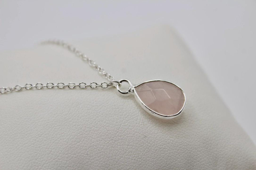 Silver necklace with a teardrop-shaped pendant on a light background