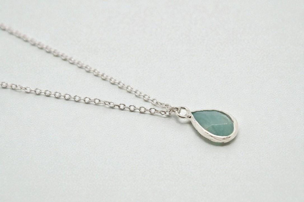 Teardrop-shaped pendant necklace on a light gray background