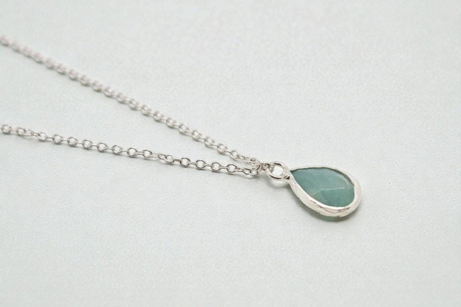Teardrop-shaped pendant necklace on a light gray background