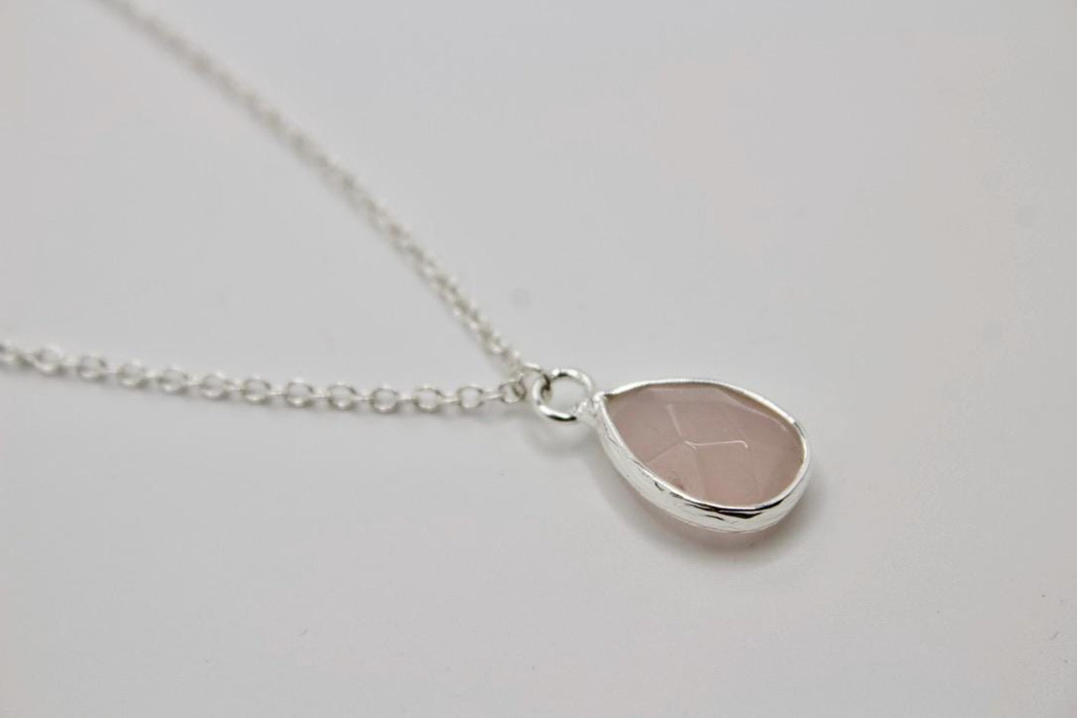Teardrop-shaped pendant necklace on a light gray background